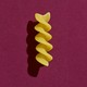 A piece of pasta on a purple background
