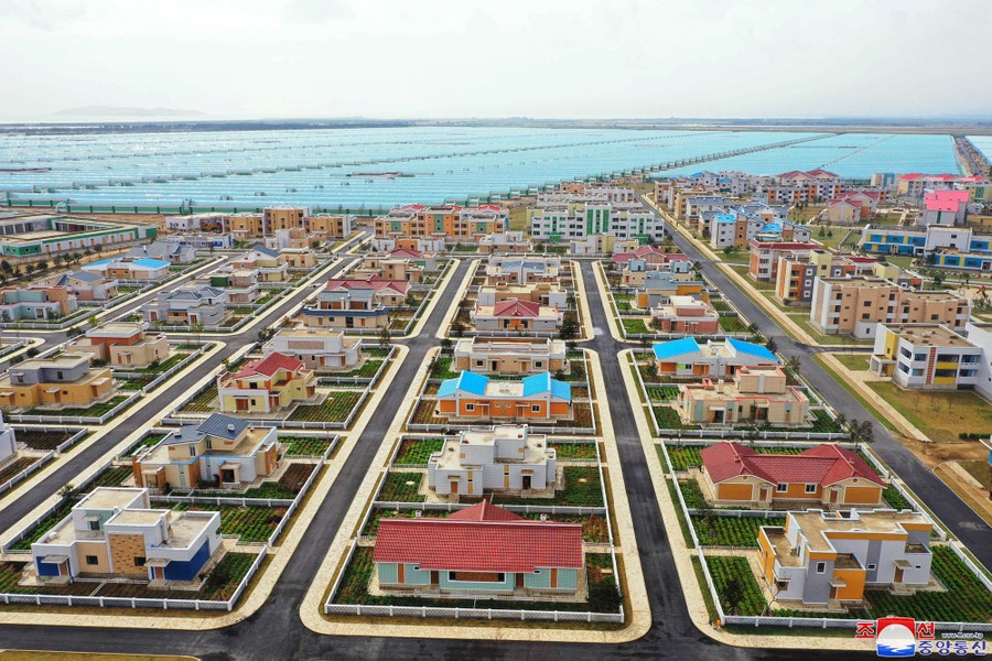 An elevated view of colorful new houses and an extensive greenhouse complex.