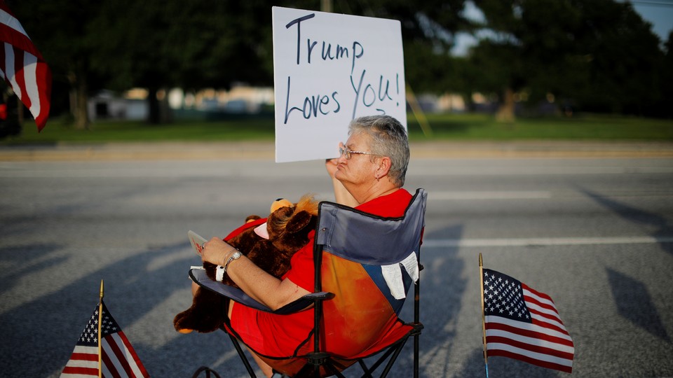 Woman holds a sign that says "Trump Loves You."