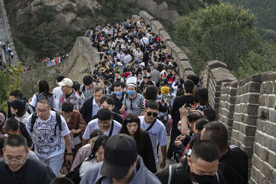 A large crowd of people walk along a section of the Great Wall of China.