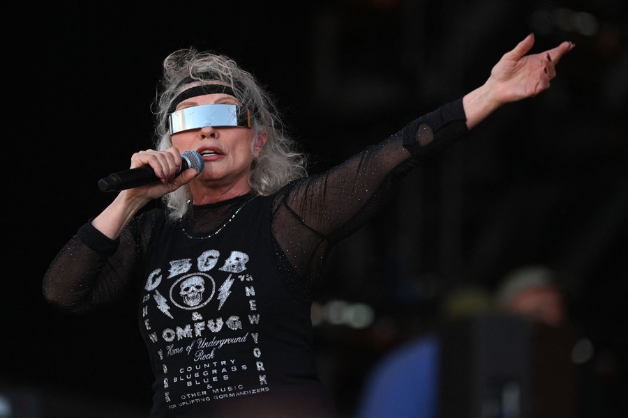 A singer, wearing a mirrored visor, performs on stage.