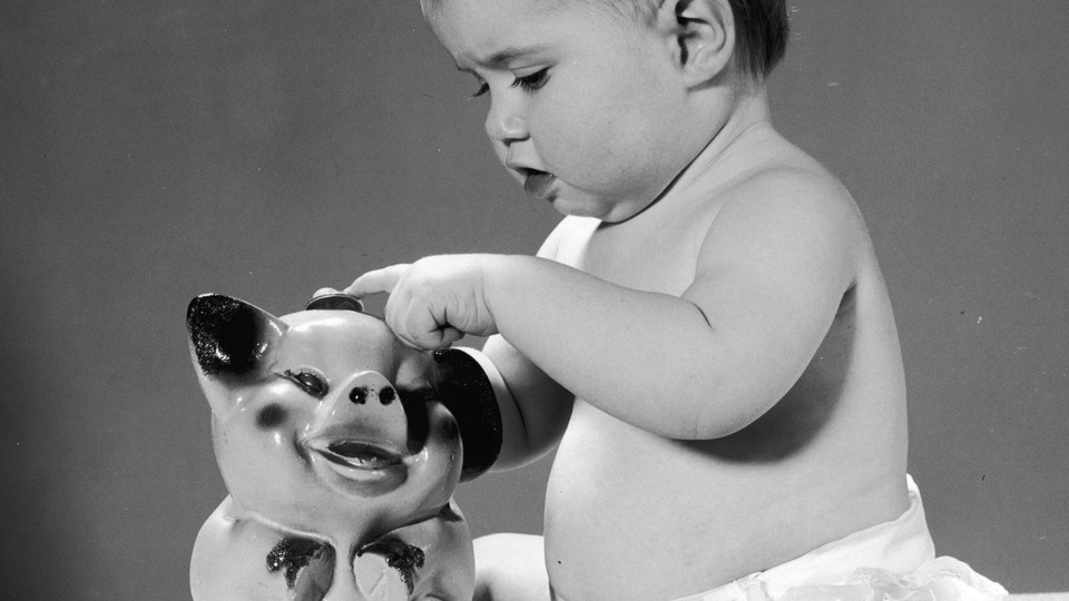 A toddler inserting coin in piggy bank