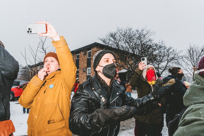 A large group of people blowing whistles and filming ICE 