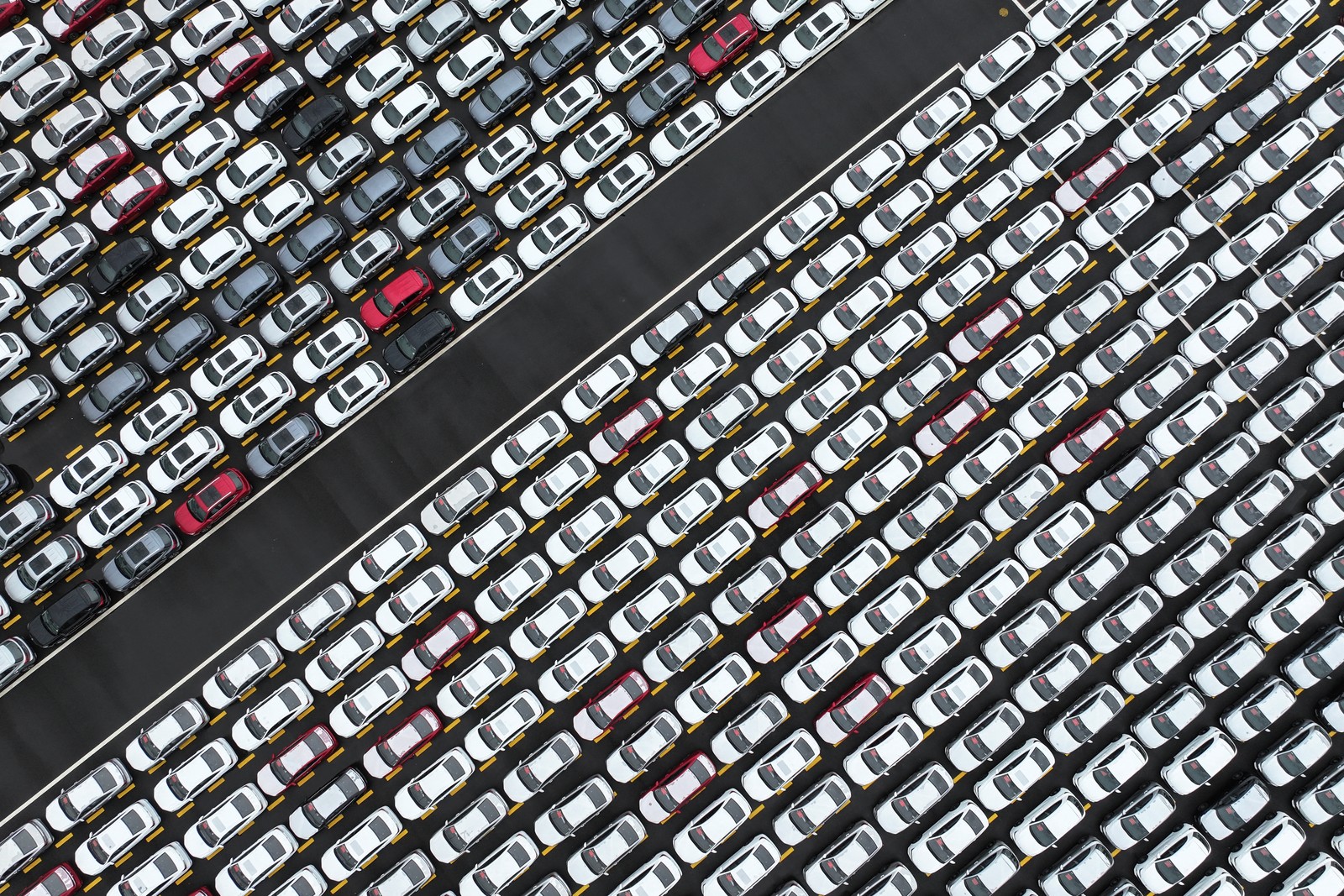 An aerial photograph of hundreds of new cars parked in straight rows