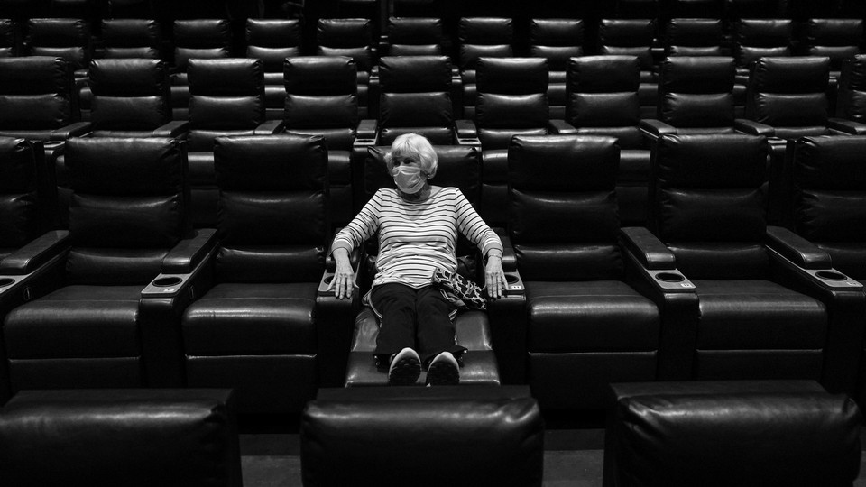 A woman sits alone in an empty movie theater