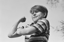 A young boy flexes his arm in a black and white photo