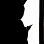 A silhouette of a person checking their phone