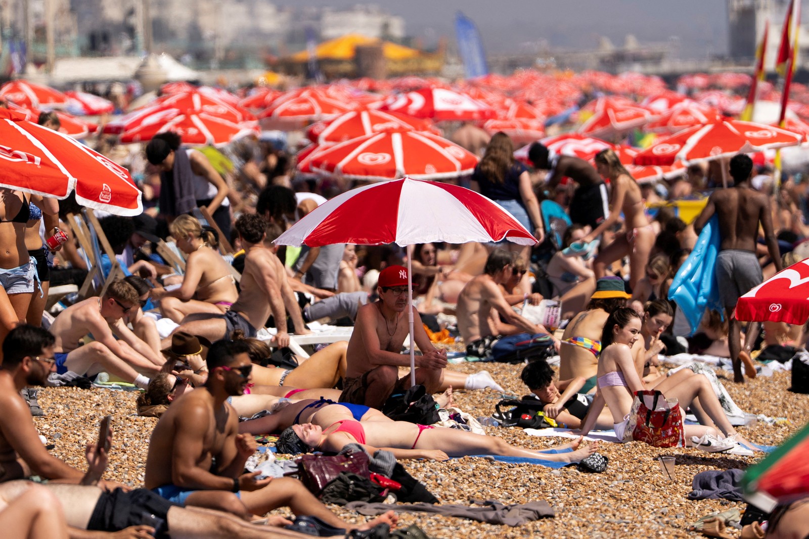 Many people on a beach on a hot day, with dozens of beach umbrellas