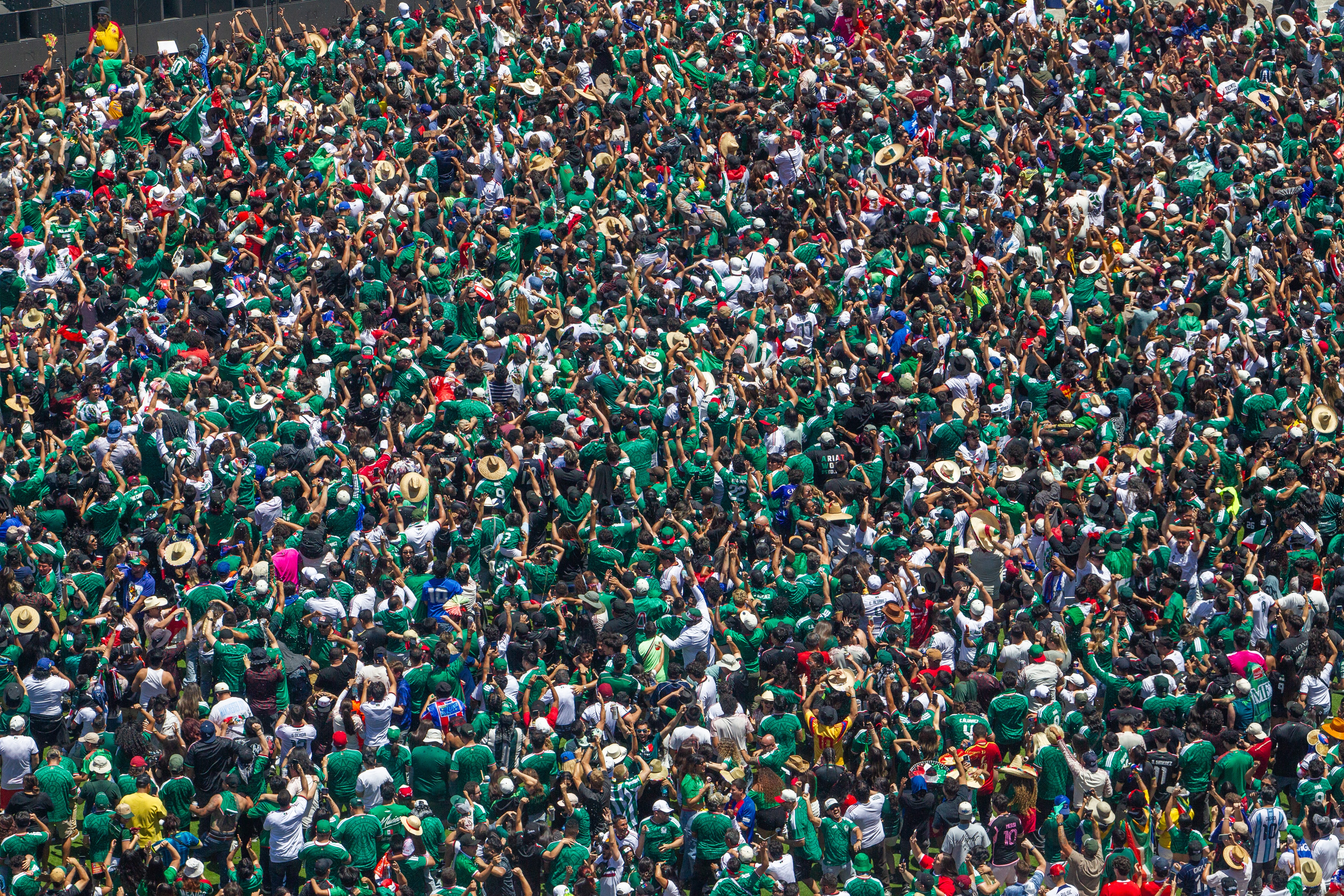 An elevated view of a big crowd of cheering sports fans, most of them wearing green jerseys