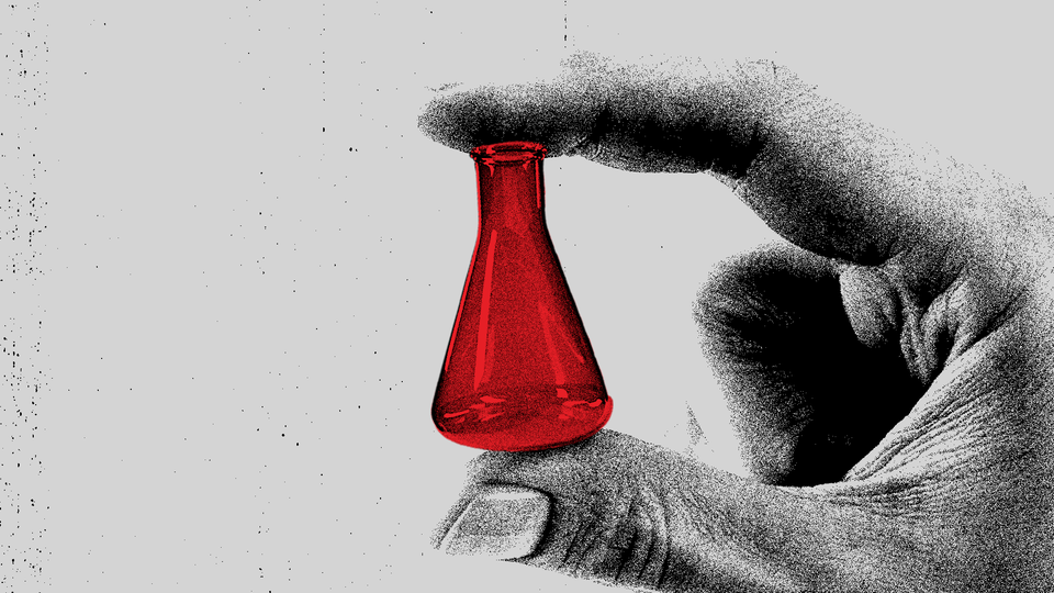 a black and white image of a hand holding a small red flask