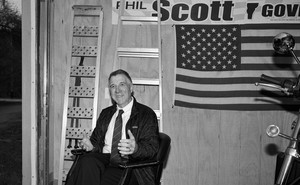 Governor Phil Scott in a garage with an American flag and a motorcycle