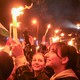 A crowd celebrates Hungarian-election results, waving flags and holding candles.