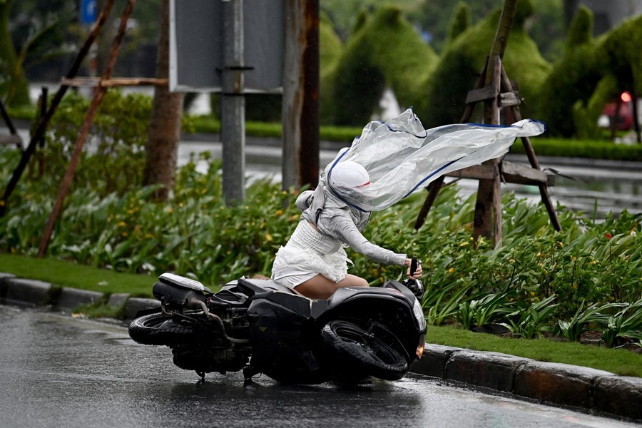 A woman riding a motorbike is blown down by typhoon winds.