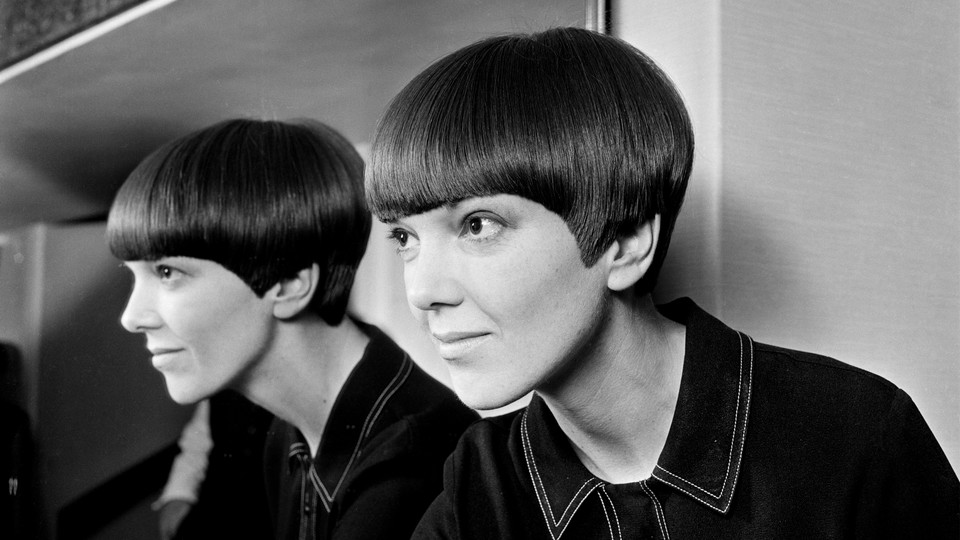 Black-and-white image of Mary Quant in the 1960s with a short bob, reflected sideways in a mirror