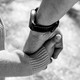 Black-and-white close-up image of an adult hand holding a child's hand