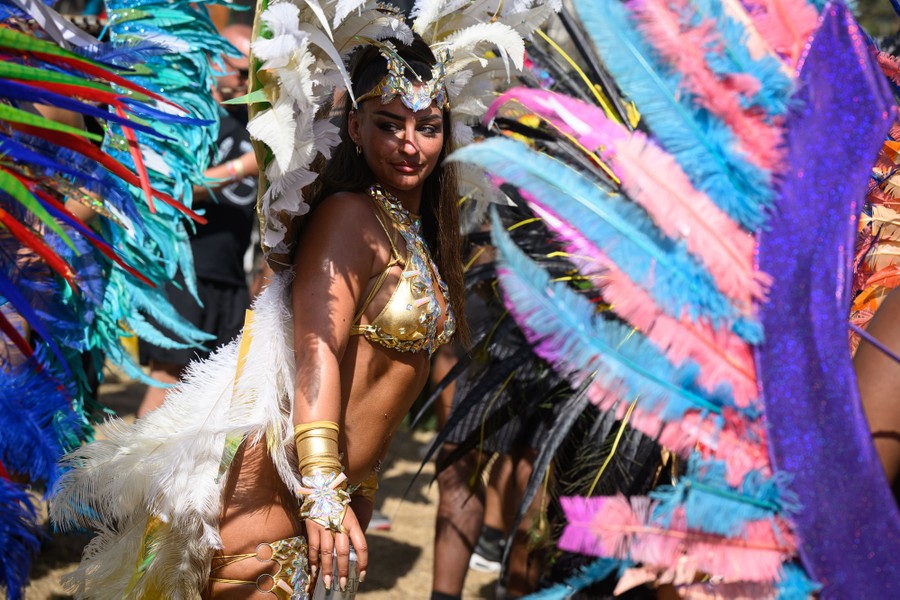 Carnival performers in feathery costumes dance.