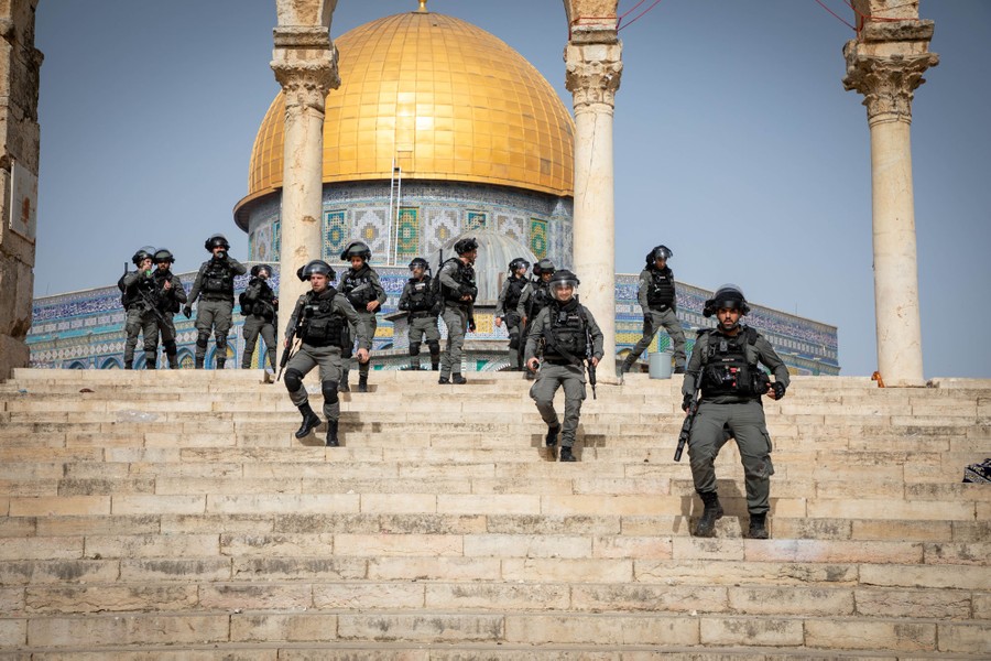 More than a dozen riot-police officers walk down broad steps near Al-Aqsa Mosque.