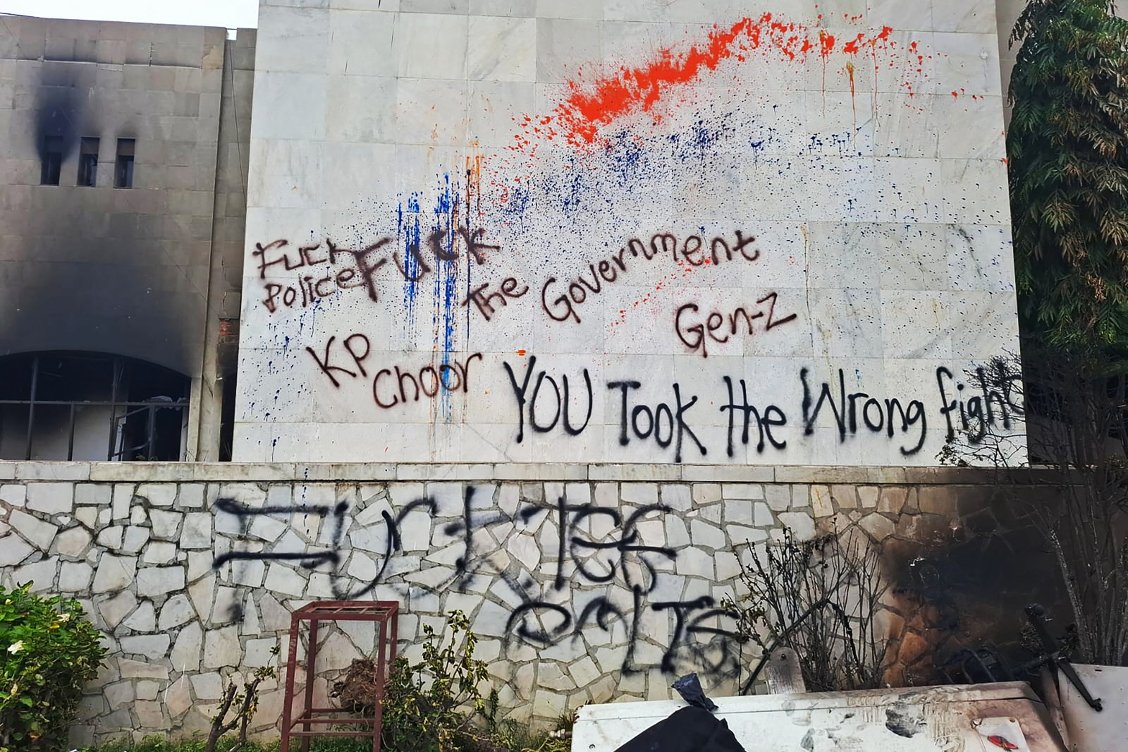 Graffiti spray-painted on a wall, reading, in part,