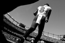 Black-and-white photo of football quarterback No. 8 poised to start running in crowded stadium