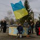 Ukrainians kneeling in a show of mourning, as one person holds a Ukrainian flag.