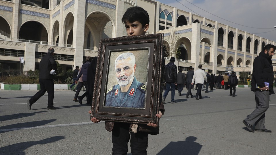 A boy carries a portrait of the Iranian Revolutionary Guard Corps general Qassem Soleimani.
