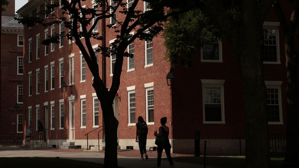 Photograph of pedestrians passing by a red brick dormitory in Harvard Yard at Harvard University