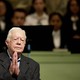 Jimmy Carter stands before a Sunday-school class, clasping his hands together.