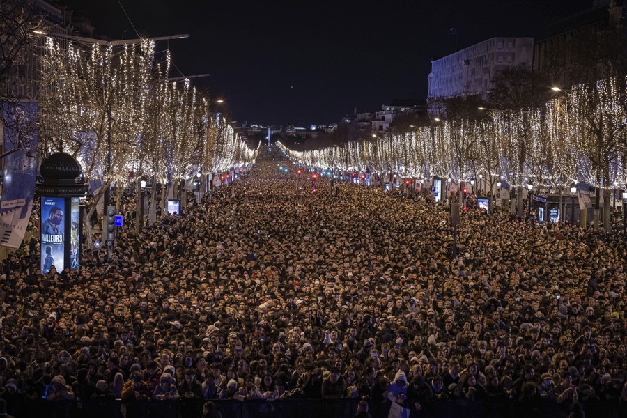 A huge crowd fills a Paris boulevard at night.