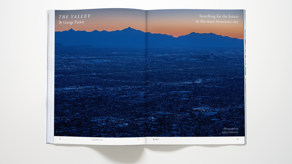 Photo-illustration of the July/August 2024 Atlantic magazine open to the story spread "The Valley" by George Packer, which features a large color photograph of an urban landscape with mountains in the distance.