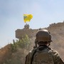A U.S. soldier watches Syrian Democratic Forces raise a flag in the background.