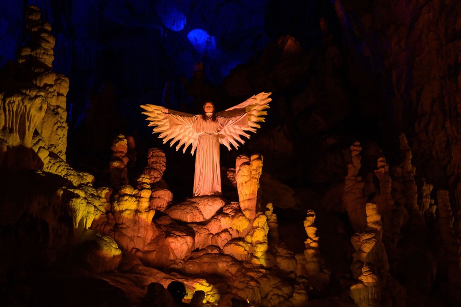 An actress dressed as an angel performs a live nativity scene inside a huge natural cave.