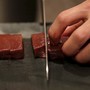 A knife chops a line or raw beef.