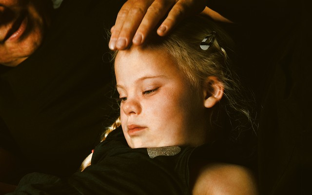 parent with hand on head of young girl