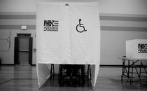 A person using a wheelchair votes at a wheelchair-accessible voting booth.