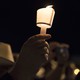 A hand holding a candle at a nighttime vigil