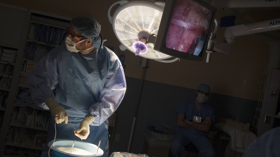 A doctor looking away from a monitor showing a kidney during a transplant operation