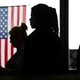 Voter are silhouetted near the American flag while voting in the California Statewide Special Election at the Huntington Beach Central Library in Huntington Beach Tuesday, Nov. 4, 2025.