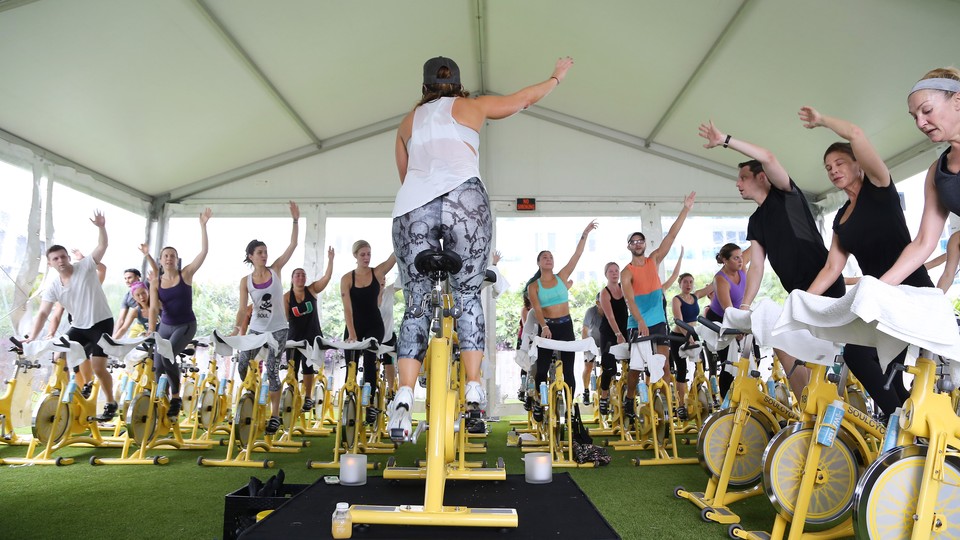 People ride yellow stationary bikes in an outdoor SoulCycle class.
