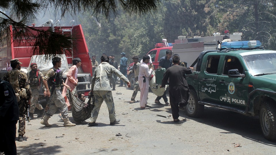Afghans carry an injured man after a suicide car bombing in Helmand province on June 22, 2017.