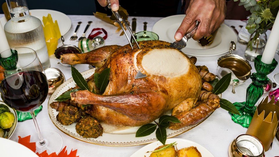 A man carves a Thanksgiving turkey on a dinner table