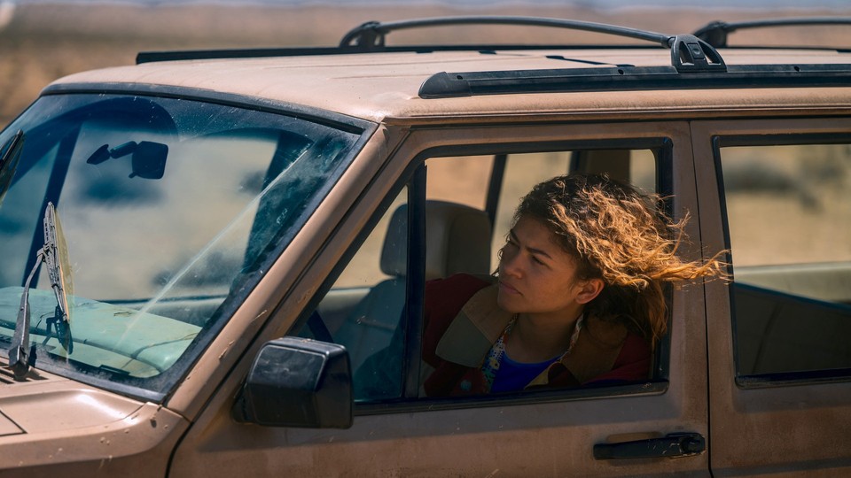 Zendaya as Rue sticks her head out of the driver's side window of a dirty car.