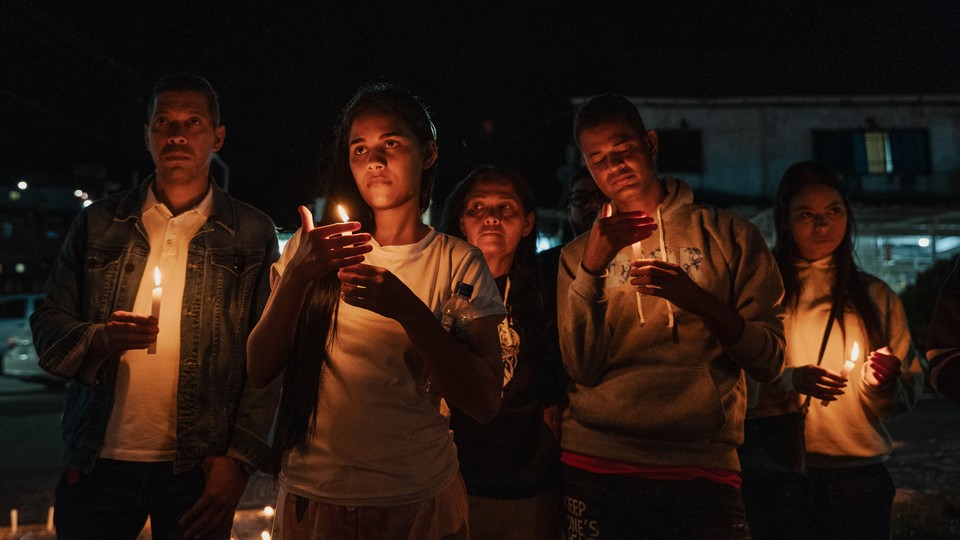 Family members of political prisoners hold photographs of their loved ones and candles during a nighttime vigil.