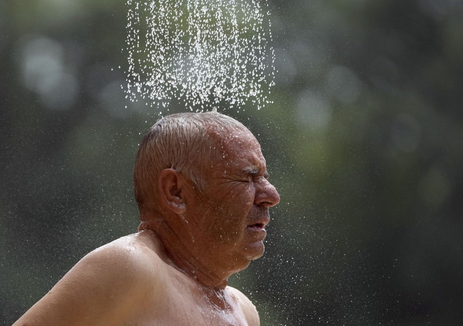 Water from a shower head falls on a man's head.