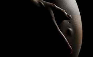 A hand on a pregnant person's stomach