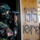 A Filipino soldier uses binoculars next to a wood panel where the words ' ISIS here' are spray-painted.
