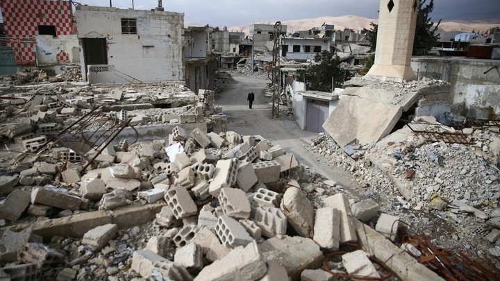 A man walks past damaged buildings in the rebel-held besieged city of Douma.