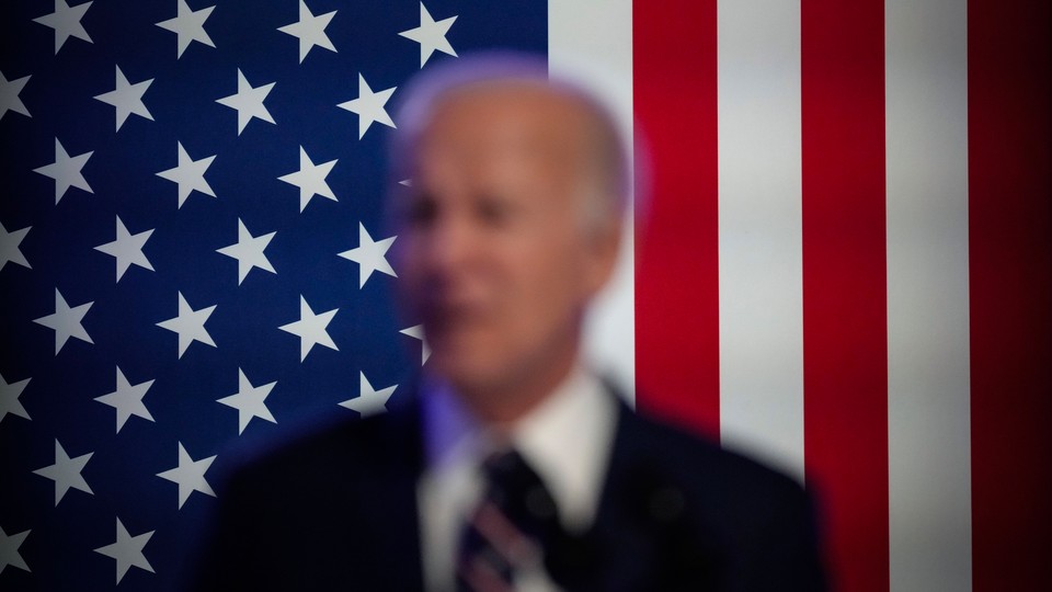 A blurry picture of Biden, the American flag in the background