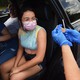a masked person prepares to receive a COVID-19 vaccine
