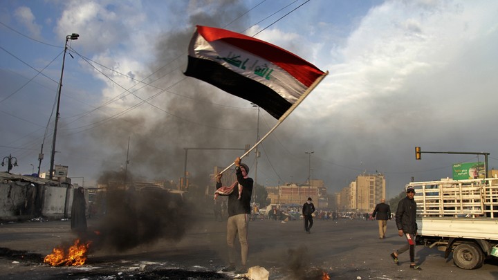 Protester waving Iraq flag after missile strike in Baghdad