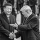 Fotografía en blanco y negro de Xi Jinping estrechándole la mano a Donald Trump, quien le hace un gesto, con una fila de guardias uniformados en posición de firmes al fondo.